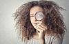 A woman holding a magnifying glass to her eye