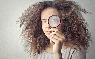 A woman holding a magnifying glass to her eye